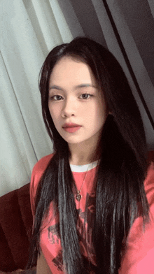 a girl with long black hair is wearing a red shirt that says ' abercrombie & fitch ' on it