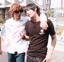 a man wearing a black shirt with a cross on it stands next to another man