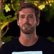 a man with a beard is wearing a black shirt that says l' essentiel