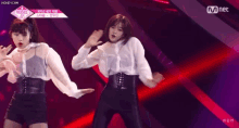 two women are dancing on a stage in front of a mnet logo .