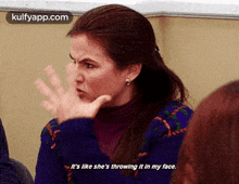 a woman is throwing something in her face while sitting in front of a group of people .