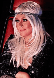 a woman with blonde hair and a headband is sitting in a red chair