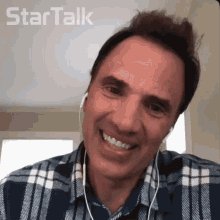 a man in a plaid shirt is smiling in front of a startalk logo