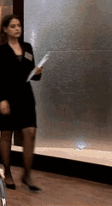 a woman in a black dress is holding a piece of paper with the word fox on it