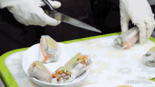 a person is cutting a roll of food with scissors on a plate that says made in animatica on it