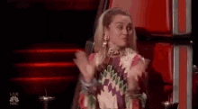 a woman is sitting in a red chair and applauding .