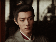 a man with a crown on his head is wearing a grey jacket