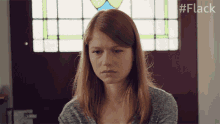 a woman sitting in front of a stained glass window with the hashtag #flack on the bottom