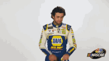 a man wearing a napa auto parts jacket stands in front of a nascar logo .