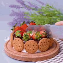 a person is cutting a cake with strawberries and cookies that say fleurs