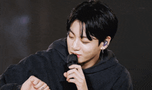 a close up of a person holding a microphone with a purple earring on their left ear