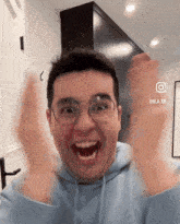 a man wearing glasses and a blue hoodie is making a face