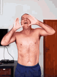 a shirtless man in blue shorts is making a funny face with his hands