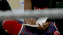 a person wearing boxing gloves is writing on a piece of paper with the number 24 in the corner