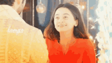 a woman in an orange shirt smiles at a man in a yellow shirt