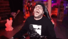 a man is sitting in a chair with his mouth open and a microphone .