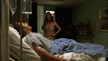 a woman in lingerie is standing next to a man in a hospital bed with a drip in his arm