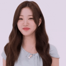 a woman with long brown hair wearing a blue shirt and necklace