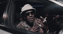 a man wearing sunglasses and a hat is sitting in a car .