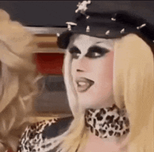 a close up of a drag queen wearing a hat and leopard print necklace .
