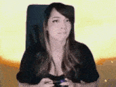 a woman is sitting in a chair holding a video game controller and playing a video game .