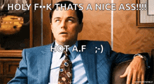 a man in a suit and tie is sitting on a couch with the words holy f k thats a nice ass !!!