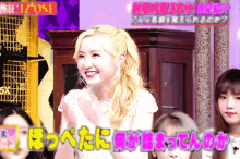 a woman with blonde hair is smiling in front of a sign that says ' izone '