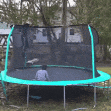 a child is sitting on a trampoline with a fence around it