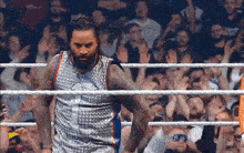 a man in a basketball jersey stands in a wrestling ring surrounded by fans
