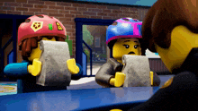a couple of lego figures sitting at a table looking at papers