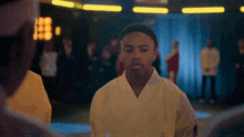 a man in a white karate uniform stands in a dark room
