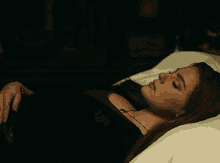 a woman laying on a bed with her eyes closed and a necklace around her neck that says ' a ' on it