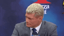 a man in a suit and tie is laughing in front of a pizza hut ad