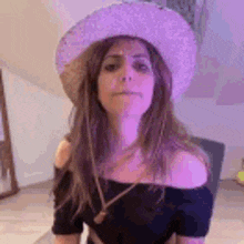 a woman wearing a cowboy hat and a black off the shoulder top .