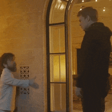 a man in a white suit shakes hands with another man in a black hoodie