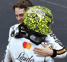 a man wearing a helmet that says monster on it is hugging another man