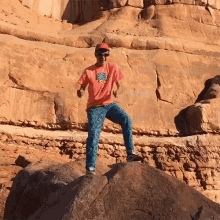 a man standing on a rock wearing a pink shirt with a sun on it