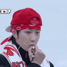 a man wearing a red bandana and a red hat is blowing a whistle .