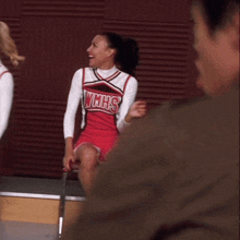 two cheerleaders are sitting on a bench and one is wearing a shirt that says ' nc '