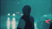 a man is standing in the rain with a car behind him