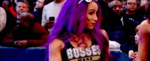 a woman with purple hair is standing in front of a crowd wearing a bosses make t-shirt .