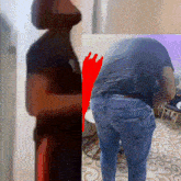 a man in a black shirt and blue jeans is standing in a living room with his back to the camera .