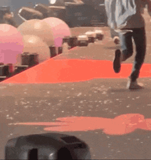 a person is running on a red carpet in front of balloons