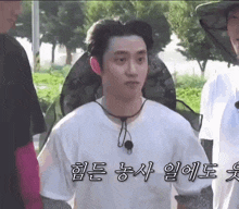 a man wearing a white t-shirt and a hat is standing next to another man in a park .
