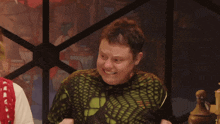 a man wearing a green sweater is laughing with his fist in the air