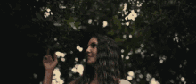a woman with long hair is standing in the woods