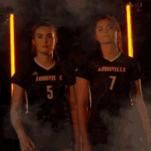 two women wearing louisville jerseys number 5 and 7
