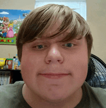 a young man looks at the camera with a mario poster in the background