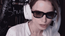 a woman wearing glasses and headphones is sitting in front of a sign that says " shut "