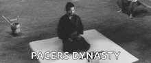 a man in a samurai costume is kneeling on a mat .